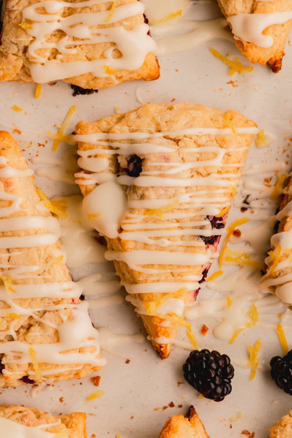 Pastry with white icing and blackberries on a light background