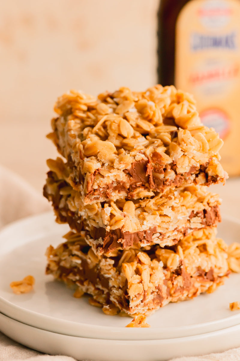 Stack of cereal bars on a white plate with a blurred bottle in the background