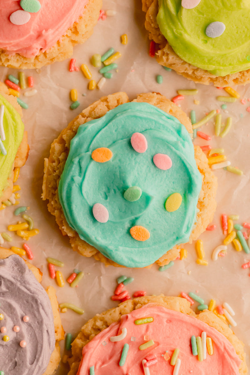 Colorful frosted cookies with sprinkles on a light brown background