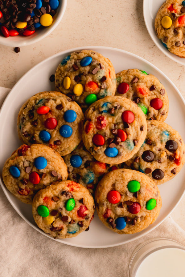 Plate of colorful M&M cookies on a beige surface