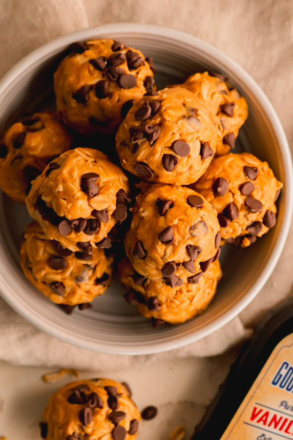 Bowl of chocolate chip cookie dough bites with a container of vanilla extract in the background.