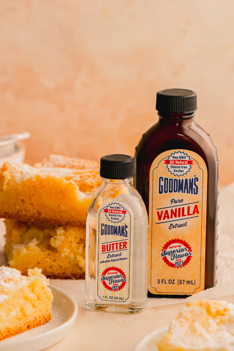 Two bottles of Goodman's vanilla and butter extract with a piece of cake in the background.