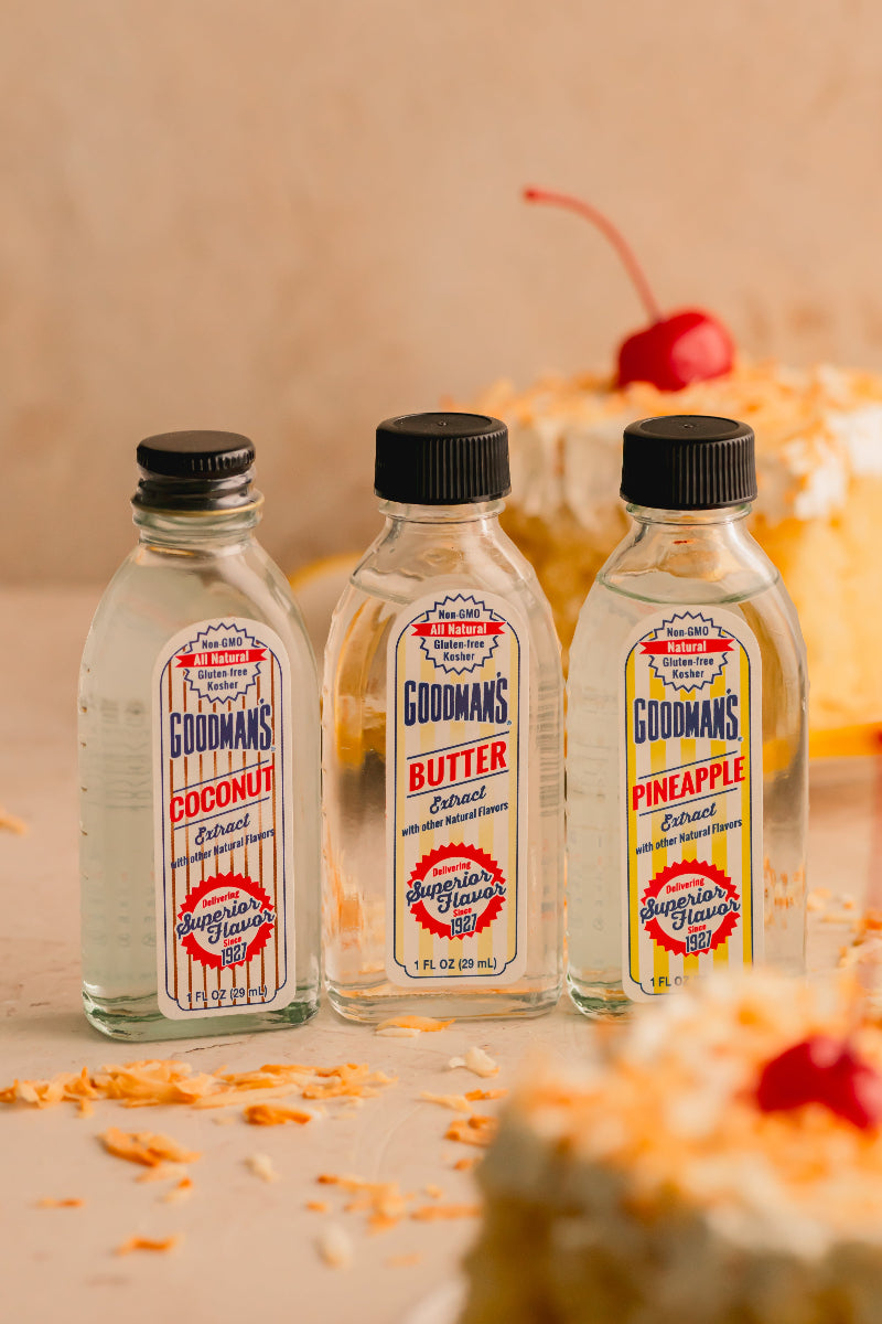 Three bottles of Goodman's Extracts with a cake in the background