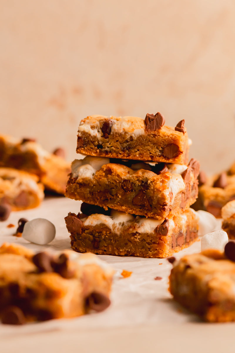 Stack of cookie bars with marshmallows and chocolate chips on a light background