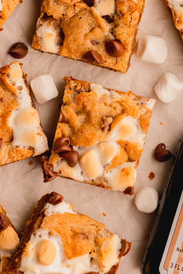 S'mores cookie bars with marshmallows and chocolate chips on a baking sheet.