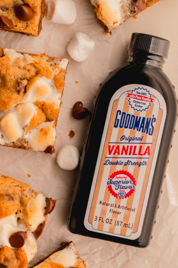 Bottle of Goodman's Vanilla extract next to dessert bars on a marble surface