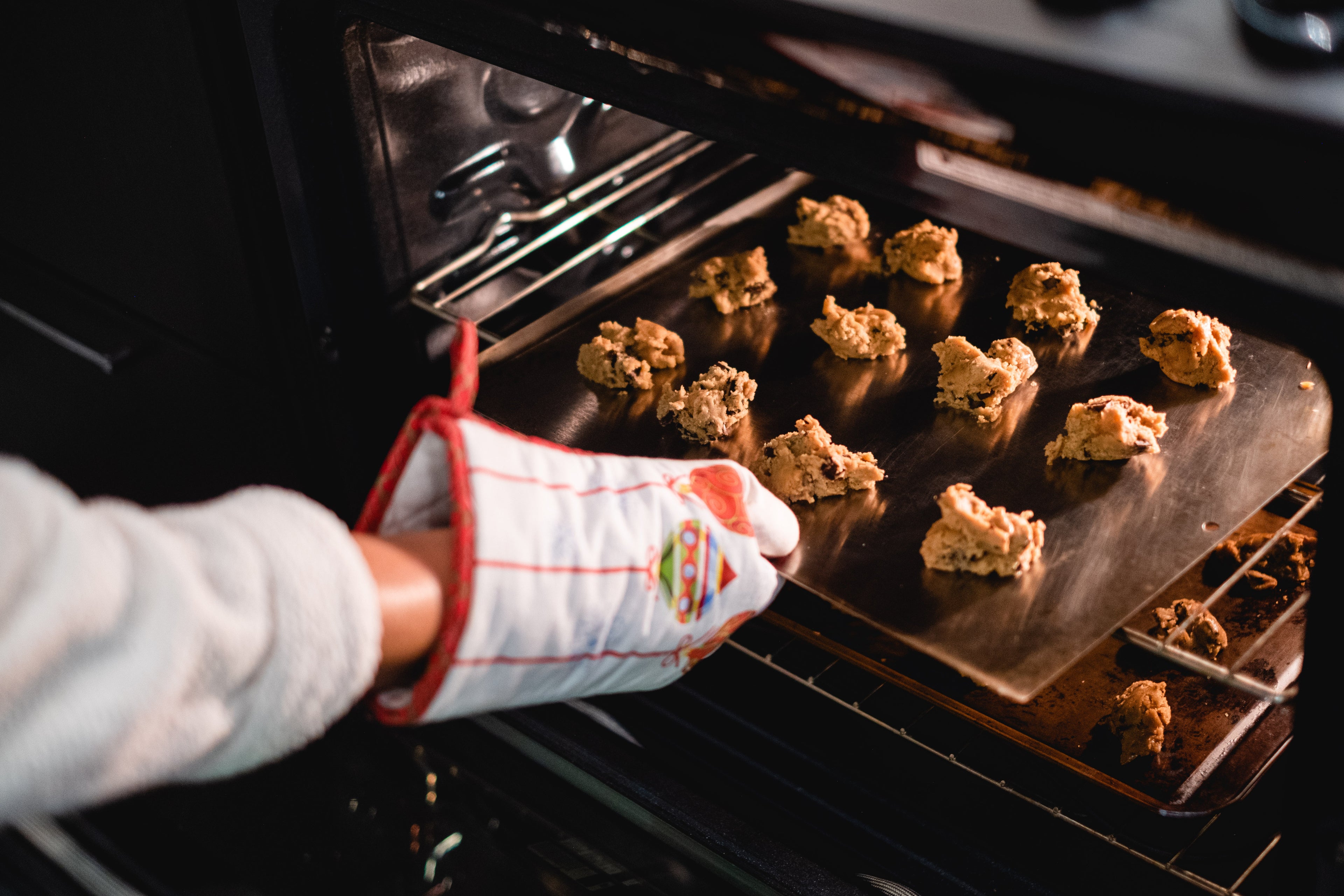 hand-with-a-oven-mit-places-cookies-into-the-oven