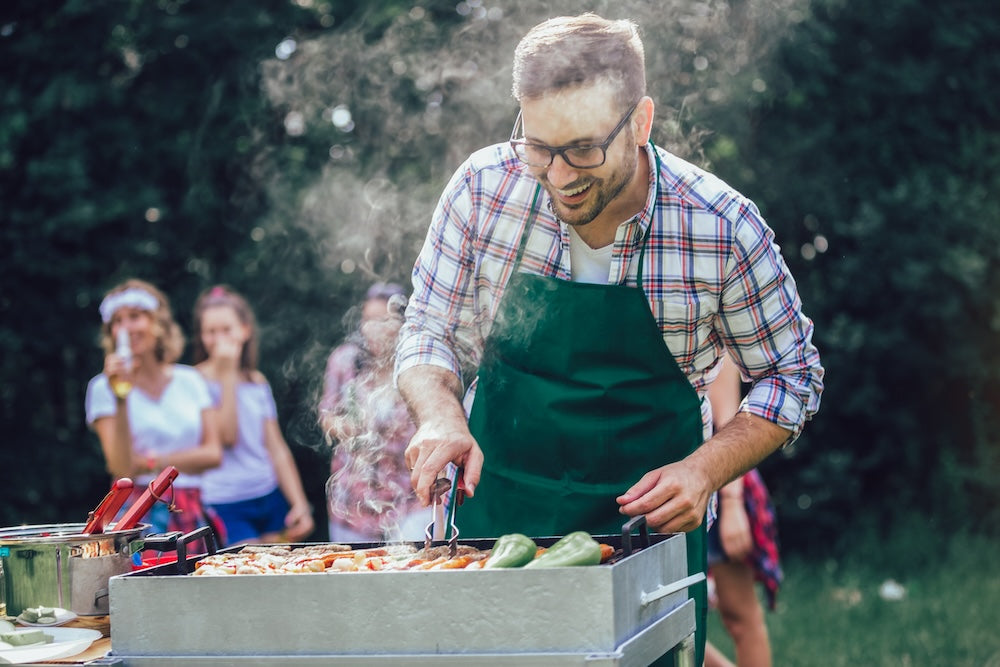 male_preparing_barbecue_outdoors_for_friends